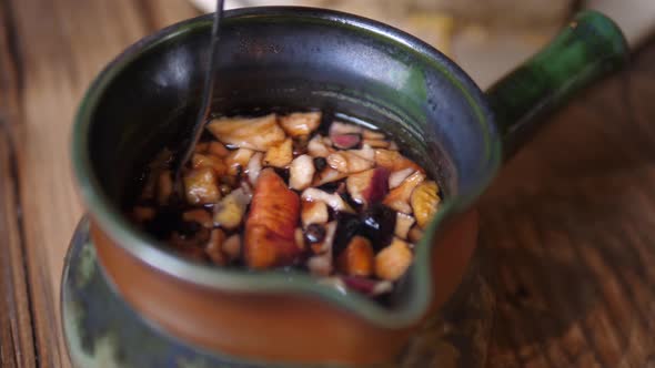 Tea Making. Hand Picks Up the Lid of Tea Kettle, Stirs Beverage with Teaspoon and Shows Dry Fruits