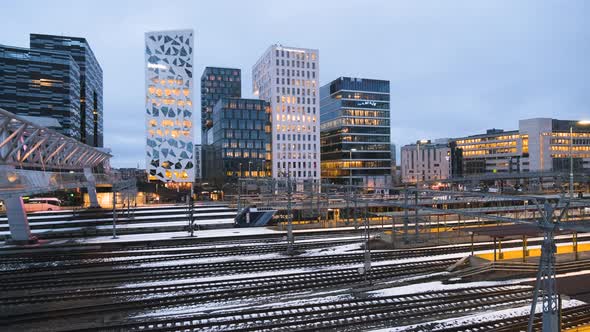 Train Travelling Under Acrobat Bridge With Illuminated Buildings On Barcode Project At Oslo, Norway.