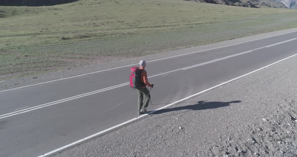 Flight Over Hitchhiker Tourist Walking on Asphalt Road
