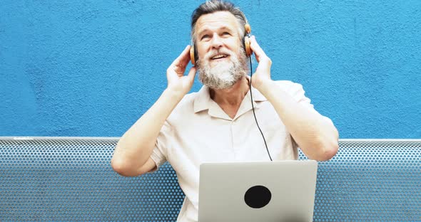 Caucasian Man 50 Years Old Happily Listening to Music with Headphones