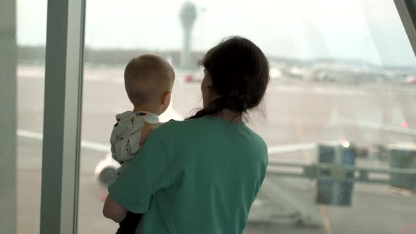 Mom with Her Son Looking at Airplane in Airport