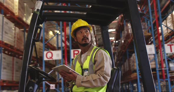 Young man working in a warehouse sitting in forklift 4k