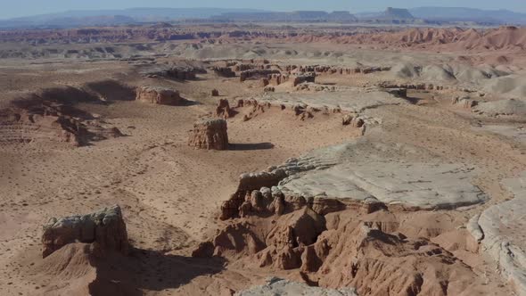 Aerial shot flying over southern Utah desert with unique canyons and rock formations in the distance