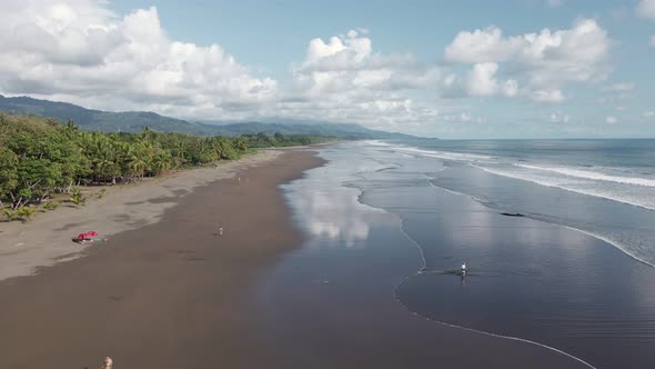 People playing in the sandy, shallow waters of Playa Linda (Matapalo), a hidden beach on the Central