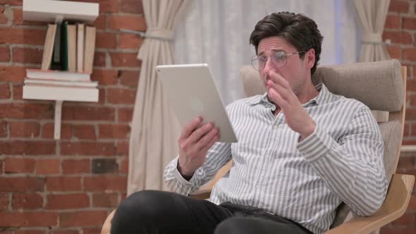 Middle Aged Man having Loss on Tablet on Sofa