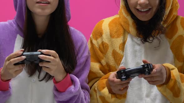 Young Women in Funny Animal Pajamas Holding Joysticks and Playing Video Games