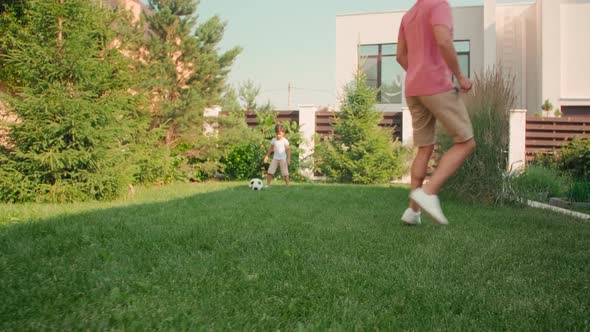 Father And Son Playing Football In Backyard