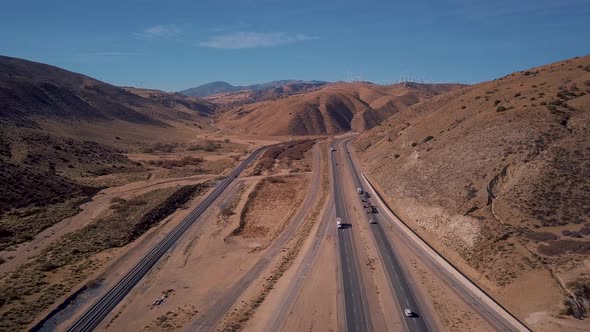 Cars and semi trucks driving on Mojave Desert highway in California, AERIAL PULL