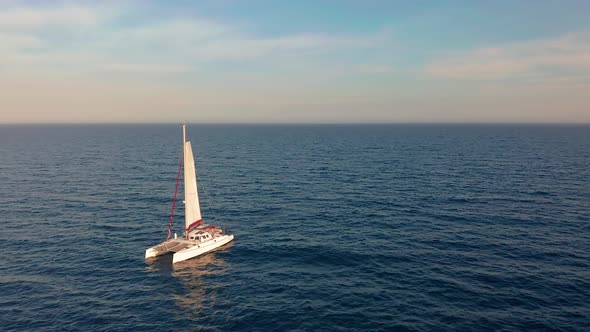 Catamaran Goes By Sea, Camera Move Closer and Fly Over Vessel, on the Sunset, Beautiful