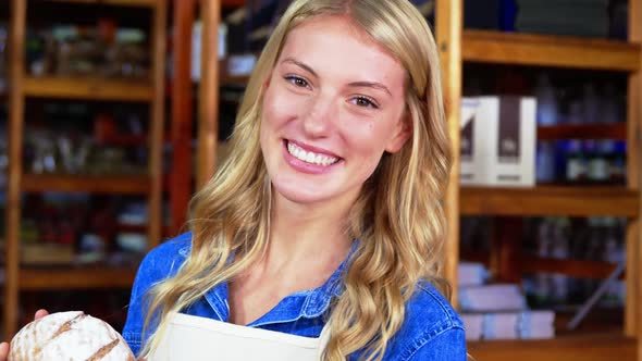 Smiling female staff holding bread in supermarket