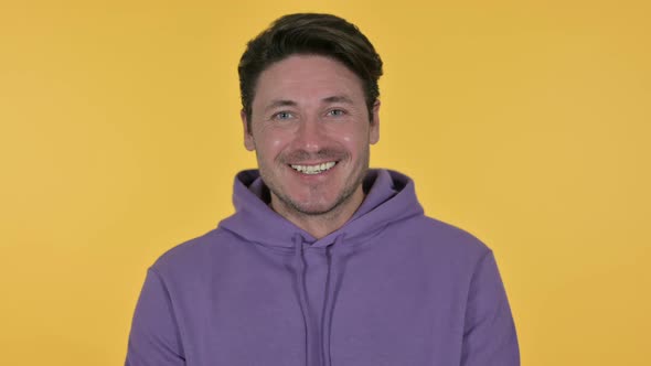 Man Smiling at Camera, Yellow Background 