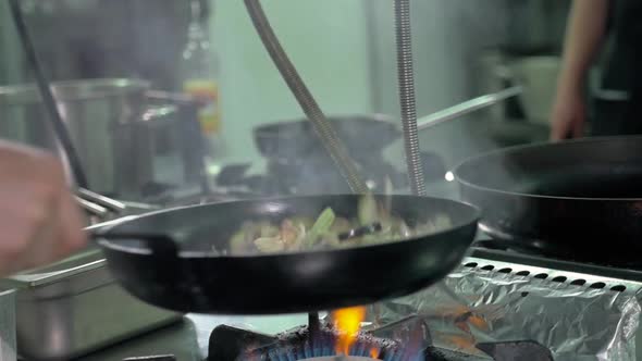 The Chef of the Restaurant Prepares Fried Vegetables in the Pan in the Kitchen Filtered Image