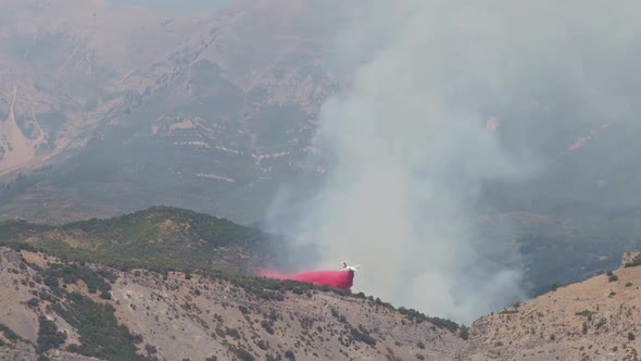 Airplane dropping fire retardant on wildfire burning on mountain in Utah