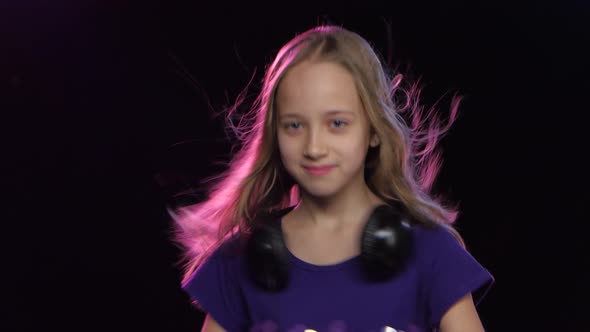 Teen Girl with Headphones Around Neck Dancing To the Music