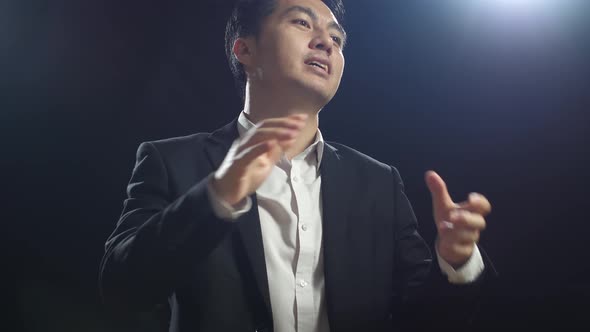 Close Up Of Asian Speaker Man In Business Suit While Speaking In The Black Screen Studio