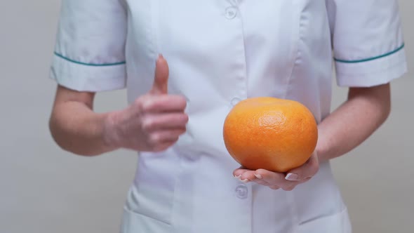 Nutritionist Doctor Healthy Lifestyle Concept - Holding Grapefruit and Medicine or Vitamin Pills