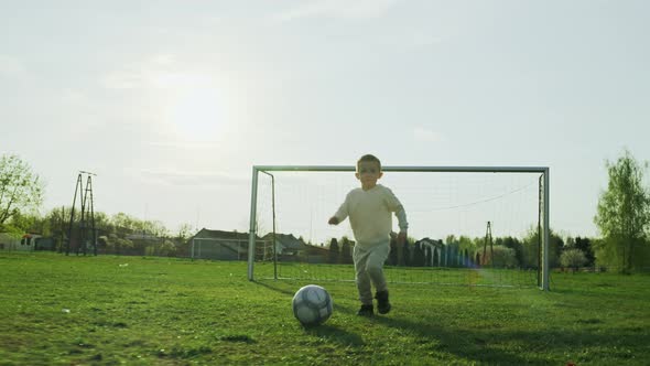 Child Runs with a Ball Playing Football