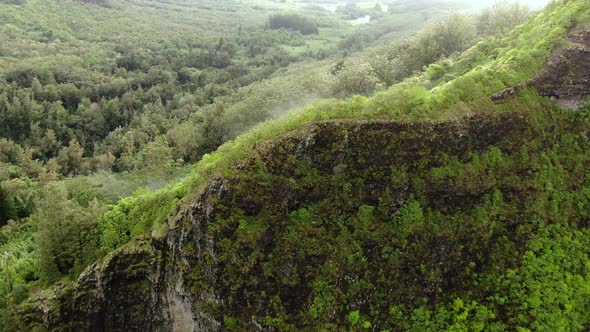 Drone flying above hikers on east oahu mountain ridge on a rainy day as fog floats above the rain fo