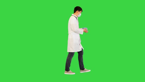 Young Asian Doctor Walks Taking Off Gloves and Mask on a Green Screen Chroma Key