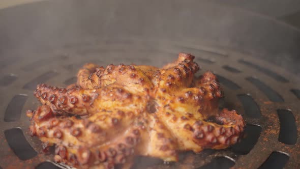 Cinematic close up shot of golden brown char-grilled smoky flavor octopus on piping hot grill.