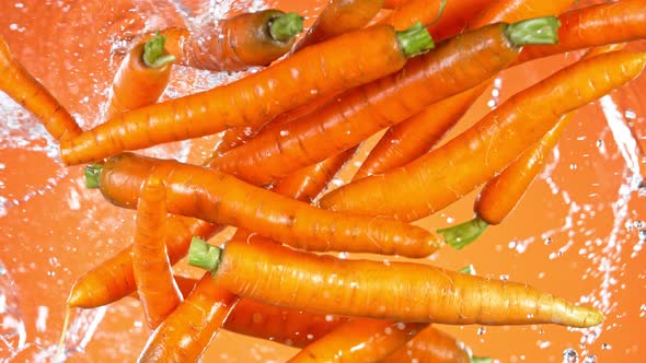 Super Slow Motion Shot of Flying Fresh Carrots and Water Side Splash at 1000 Fps