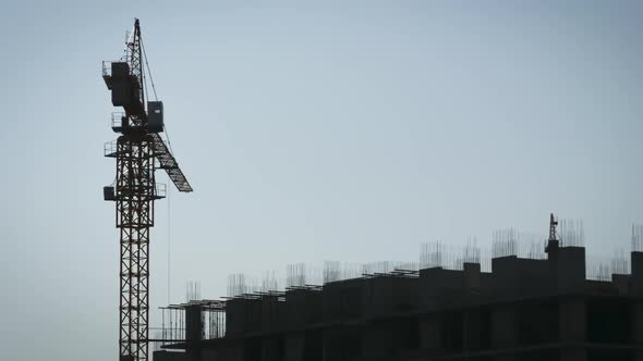 Time Lapse of Tower Cranes on a Construction Site Lifts a Load at High-rise Building