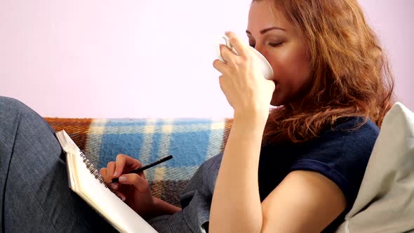  A Young Woman Works at Home at the Notepad During Quarantine. Making Notice. Social Distancing