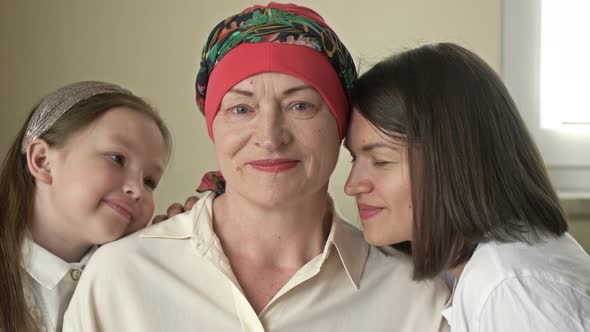 An Adult Daughter and Little Granddaughter Hug a Sad Elderly Woman Who Has Gone Bald After