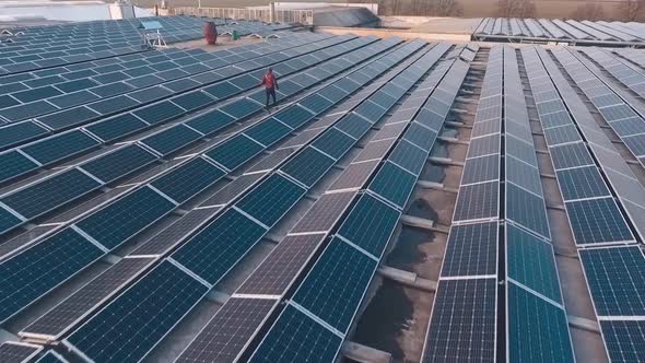 Modern solar power plant on the top of a building. Man is walking among solar cells. Alternative sou