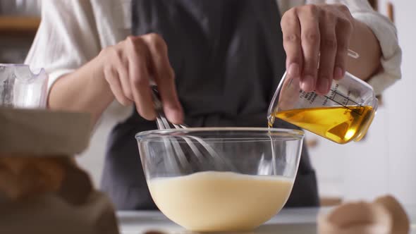 A Young Housewife Cook Mixes Batter With A Whisk Adding Sunflower Oil, The Cook Combines