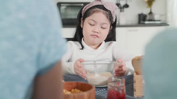 asian female child  boring food with mom and dad try to convince her to eat