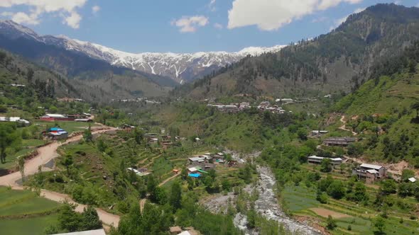 Aerial Over Road Through Swat Valley With Snow Capped Mountains In Distance. Tracking Shot