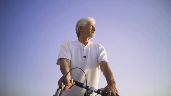 Portrait of Handsome Senior Man Riding Bike on Seafront