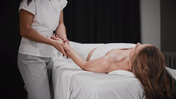 Young Woman Having a Massage Session  Lying on the Couch While the Masseuse Massaging Her Forearm