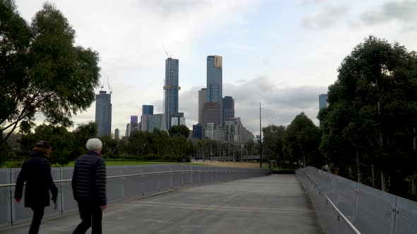 A couple walk down a Melbourne walkway with the skyline in the background - exercise during the coro