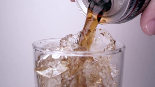 Cola pouring into glass full of ice as it fizzes