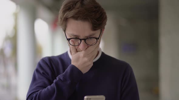 Nervous Man in Eyeglasses Using Smartphone Outdoor