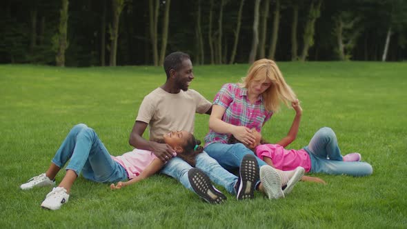 Multiracial Family with Daughters Resting in Park