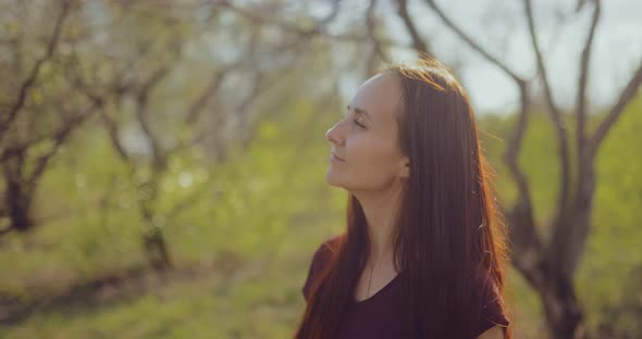 Young Happy Woman Walks in the Spring Forest and Enjoys the Weather