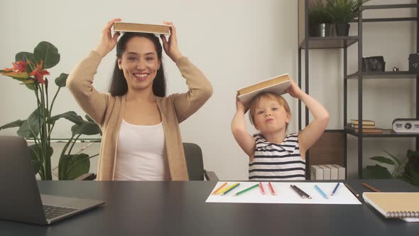 Little Girl Studying with Mother or Teacher at Study Table with Laptop Computer Books and Having Fun