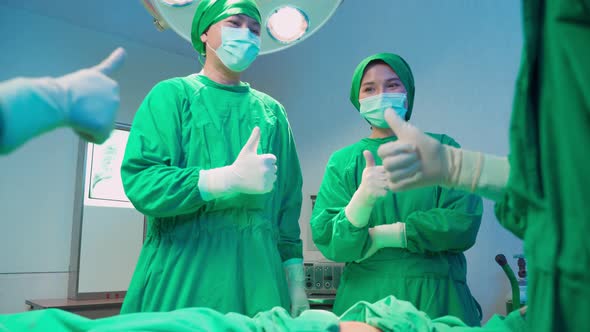 Asian medic team of surgeons and nurses suture feel glad and clap hand after success operation.
