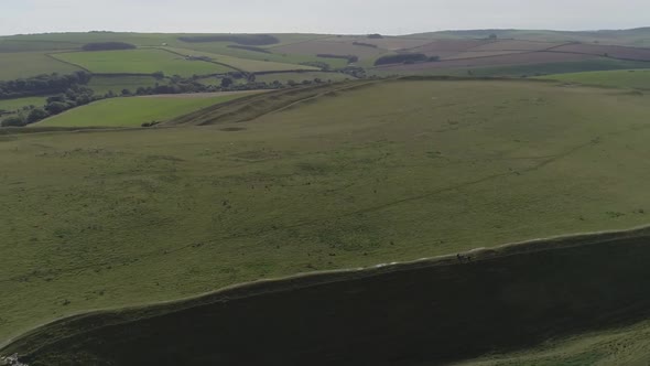 Aerial tracking around the edge of the iron age hill fort, Maiden Castle. Sheep are visible grazing