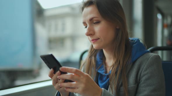 Woman in Tram Using Smartphone Chatting and Texting with Friends