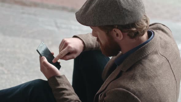 Bearded Man Browsing Internet on Steps Outside