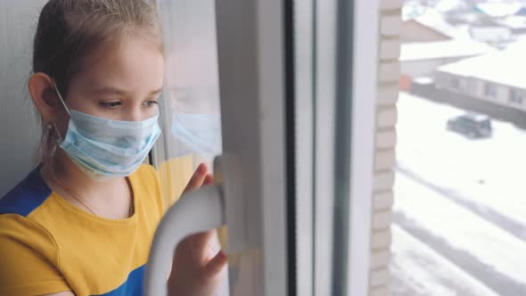 Little Girl in a Protective Mask Sits in Quarantine at Home