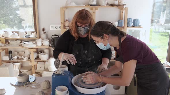 Focused women sculpturing with clay on wheel