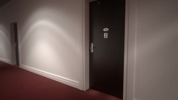 Mystery empty hotel corridor with red carpet, white walls and wooden doors.