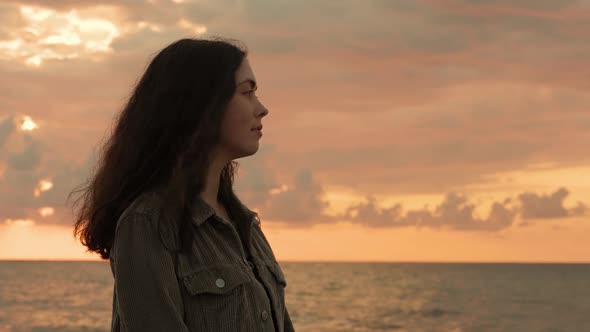 Portrait of a young beautiful woman admiring the sunset. Side view.