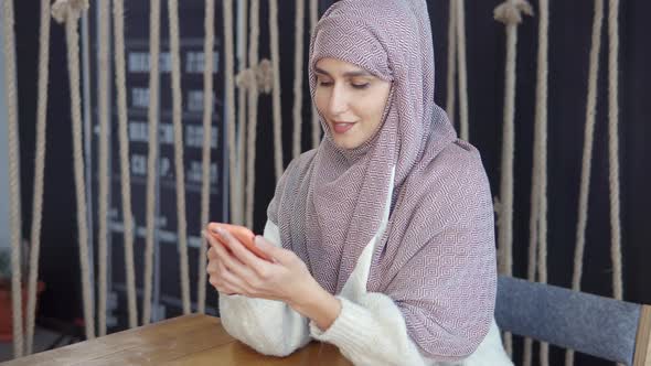 Adult Woman with Traditional Muslim Hijab on Head Typing Sms By Mobile Phone