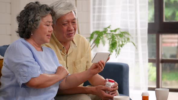 Asian senior couple having medical consultation video chat on mobile.